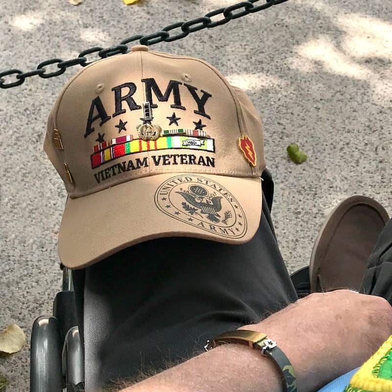 Brown Army VIetnam Veterans hat on man's knee sitting in wheelchair