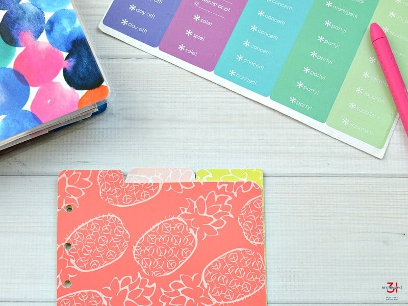 stack of 3 tabbed dividers with planner, sheet of stickers and pen in the background