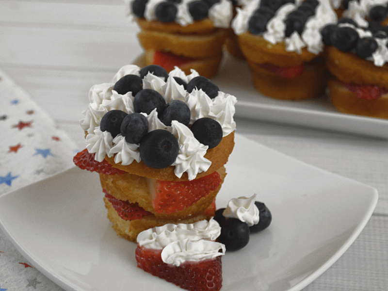strawberry shortcake with blue berries and white icing on white plate
