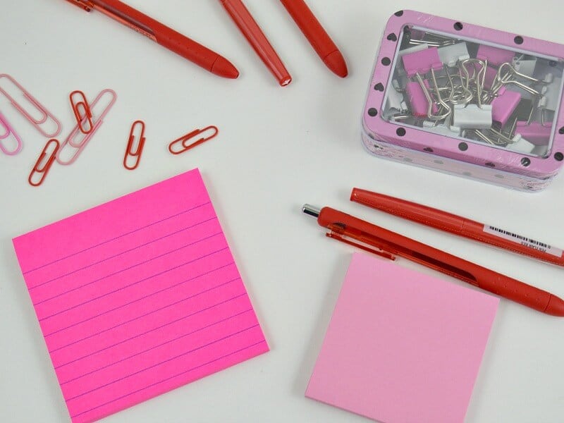 Pink and red office supplies on white table