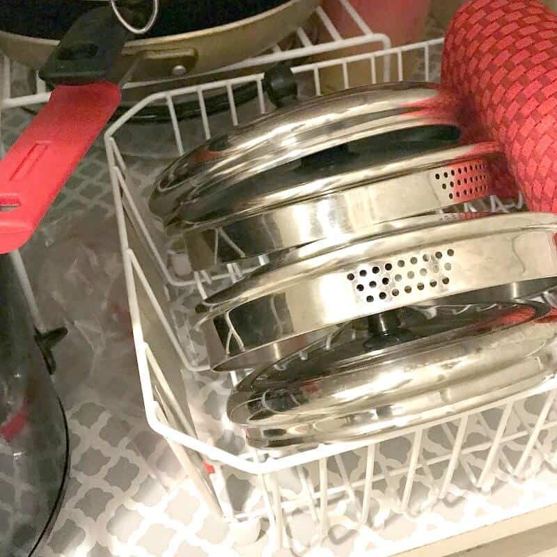 Close up of pot lids filed in dish rack.