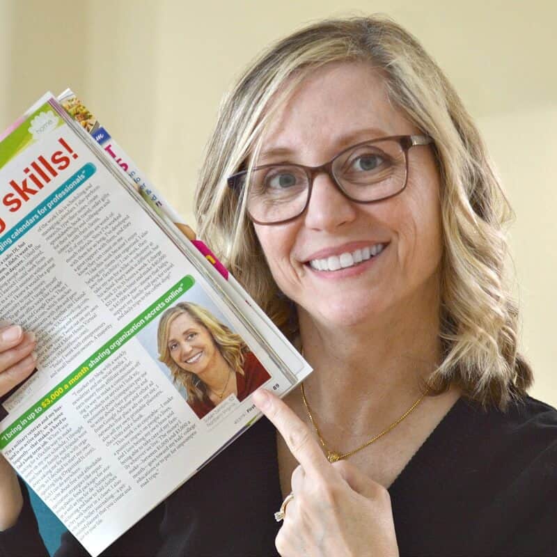 smiling blonde woman in glasses pointing to herself in a magazine