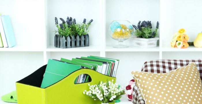 Close up of green basket holding green journals and organized bookshelf in background