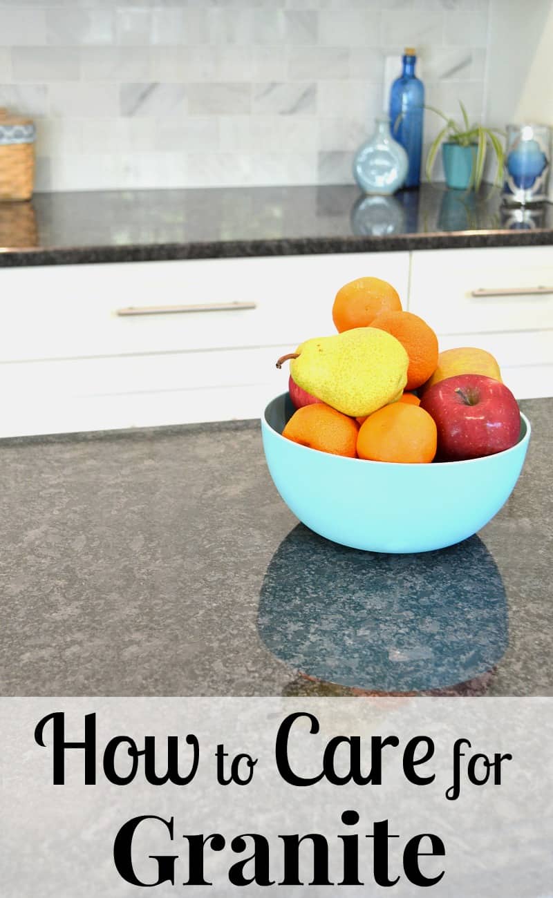 blue bowl of fruit on black granite counter with white cabinets in background with text overlay reading How to Care for Granite
