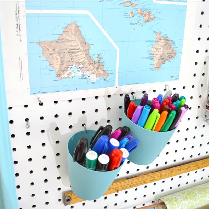 a map and two cups with markers in them hung on a peg board