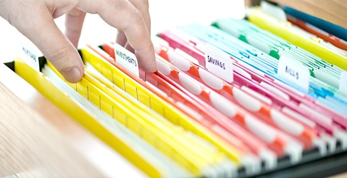 Hand flipping through brightly colored document files in file drawer