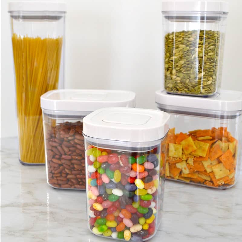 clear kitchen containers with food products like pasta, crackers, and candy.