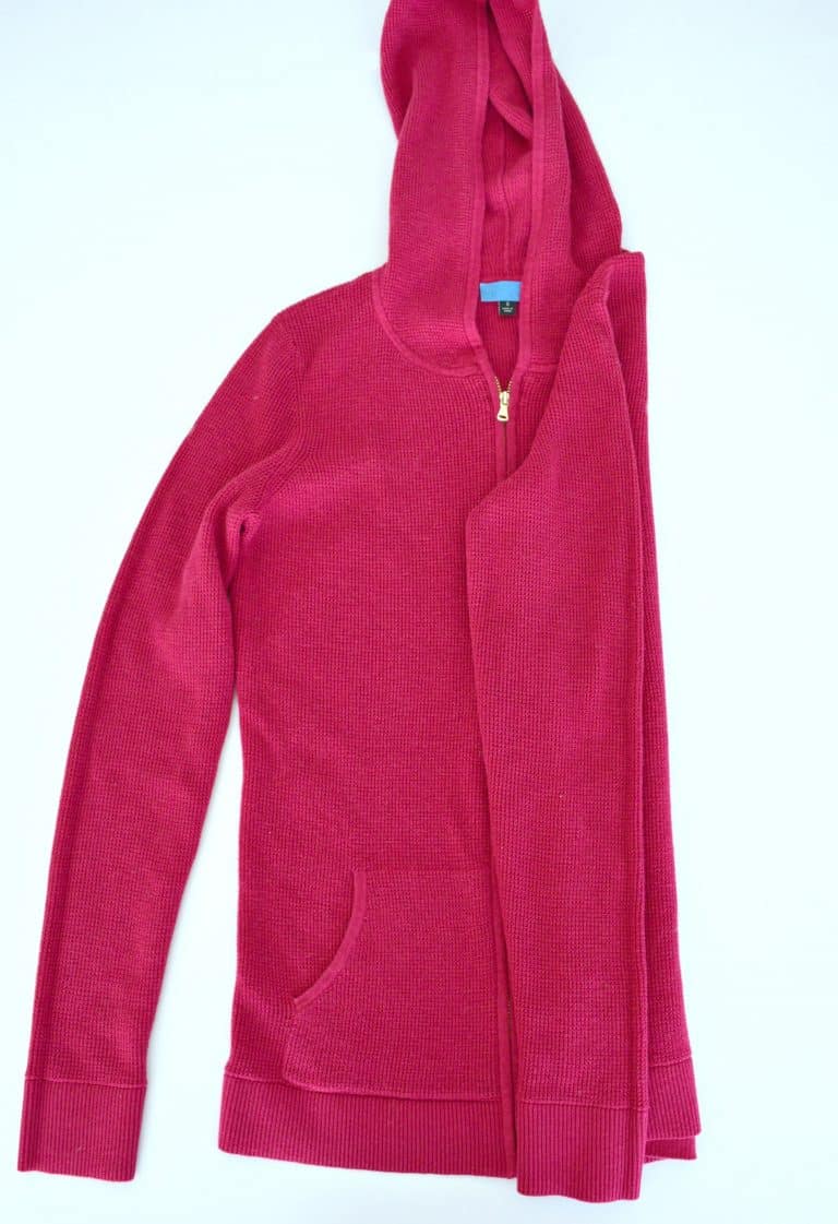 Pink hoodie with the hood up and right side and sleeve folded neatly into the middle. 