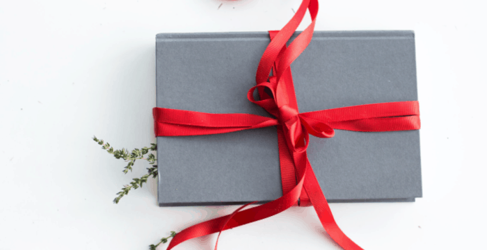 box wrapped in grey paper with a red bow