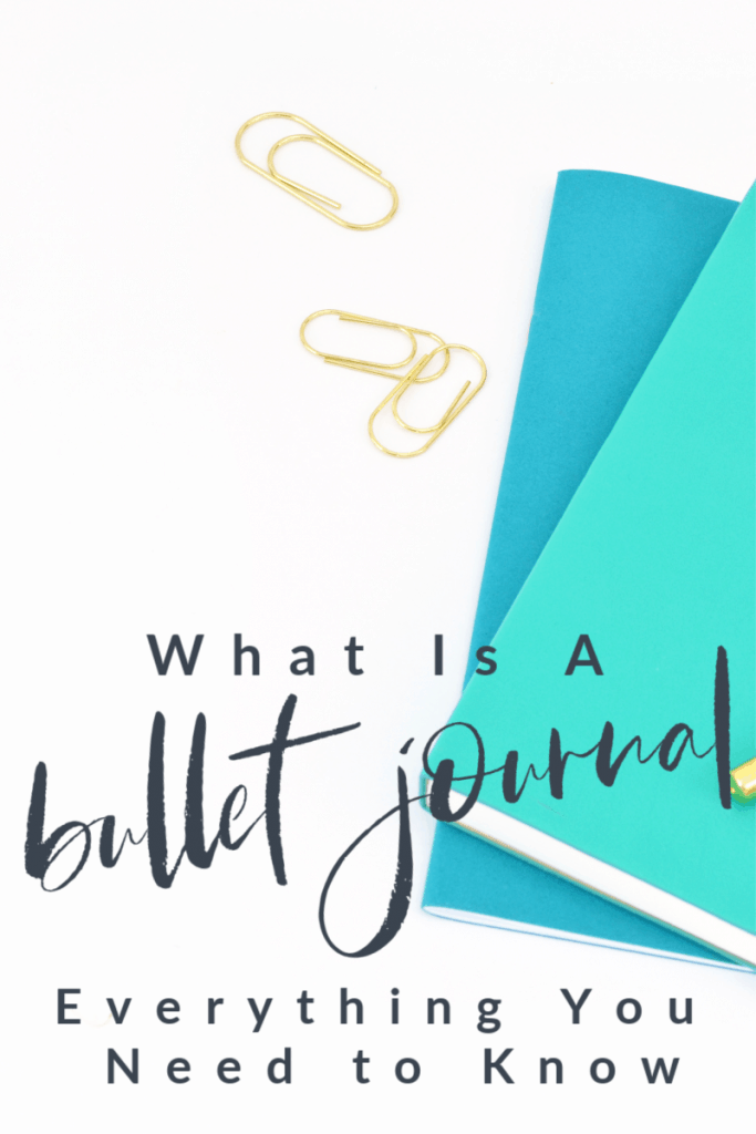 three gold paper clips and two blue journals with title What Is A Bullet Journal.