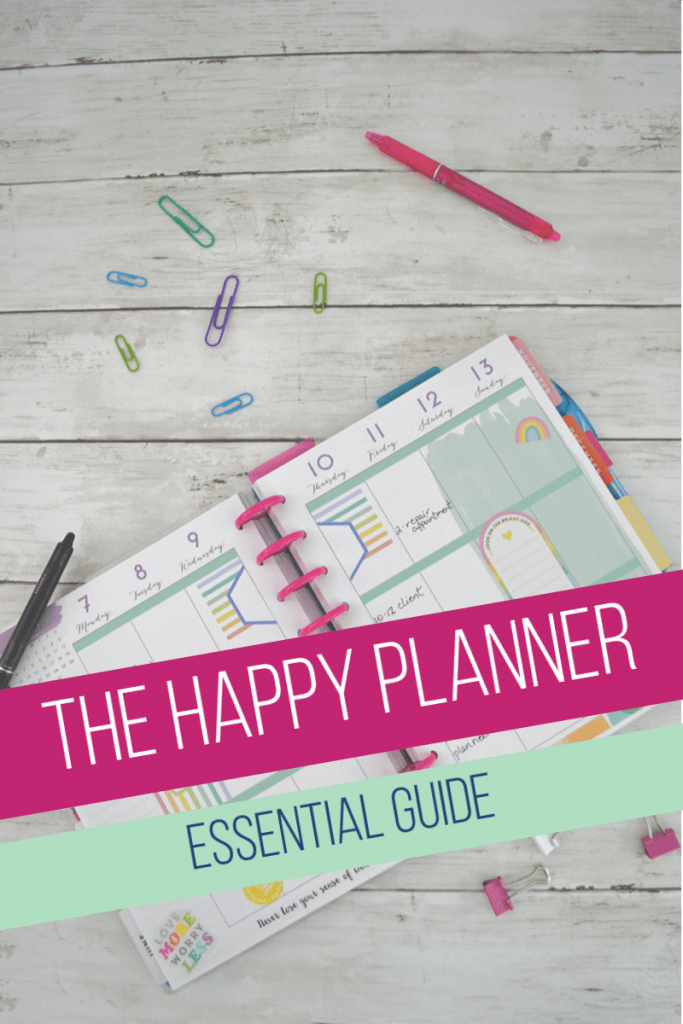 happy planner calendar with paper clips and pens on white wood table