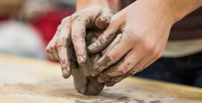 hands shaping clay pot