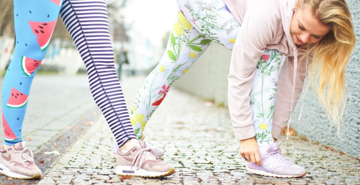 2 women in colorful attire stretching for a run