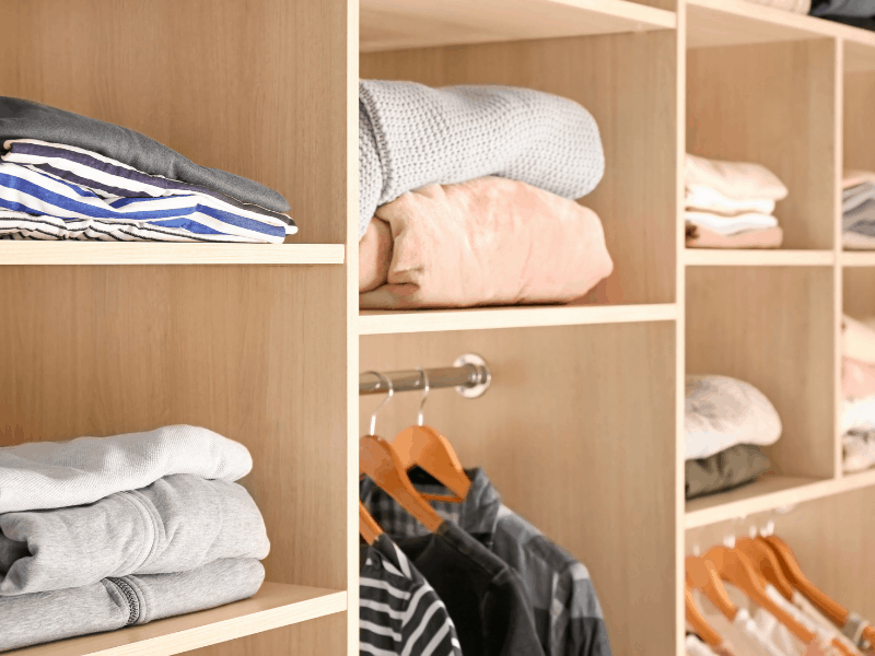 clothes neatly folded on shelves and hung in closet