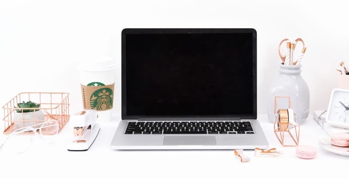 a laptop computer on a white desk top next to several other desk accessories