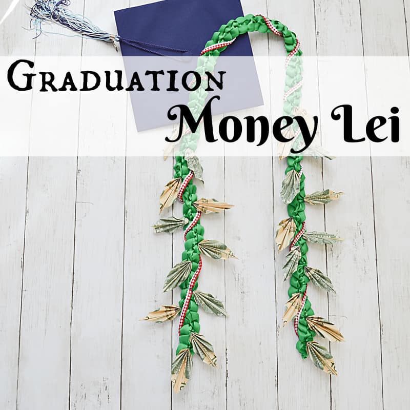 money lei and graduation cap on white wood table