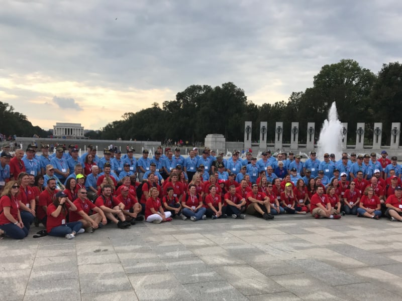 large group of veterans in blue and red shirts at World War II memorial