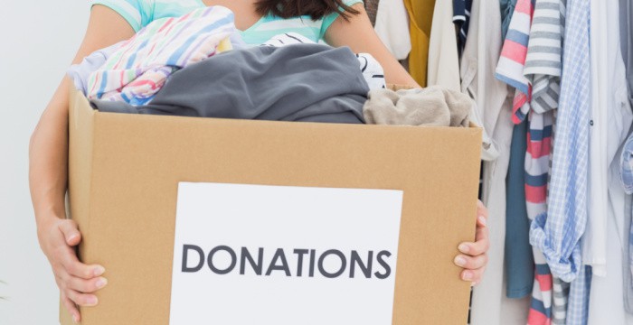 brown box with sign "donations" and filled with clothes