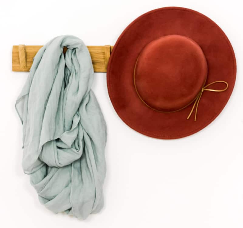 red hat and grey scarf on wood wall rack.