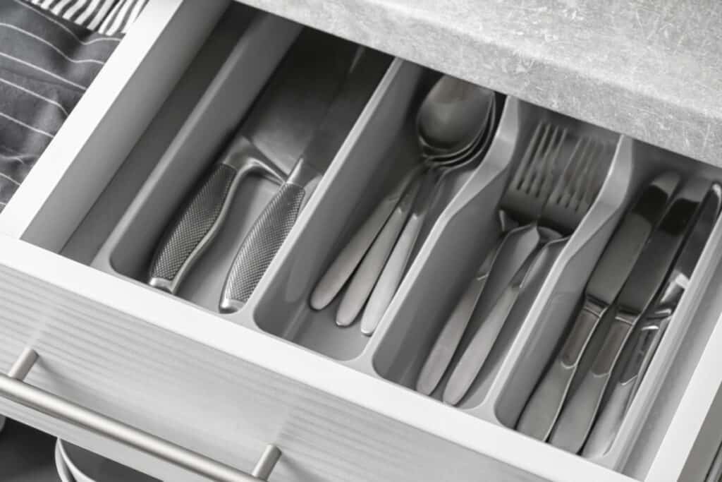 open white kitchen drawer with neatly organized silverware.