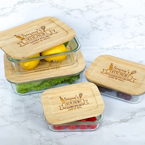 4 glass food containers with customized bamboo lids on marble counter.