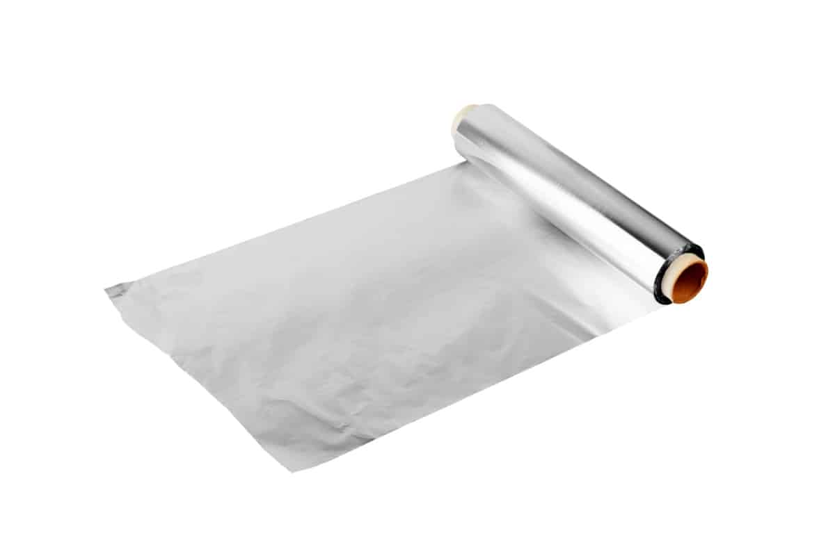roll of aluminum foil with a length pulled out from roll on white background.