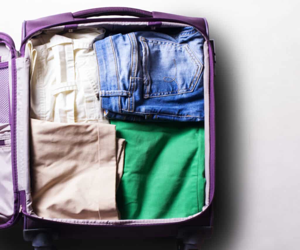 open purple suitcase with folded shorts and clothes