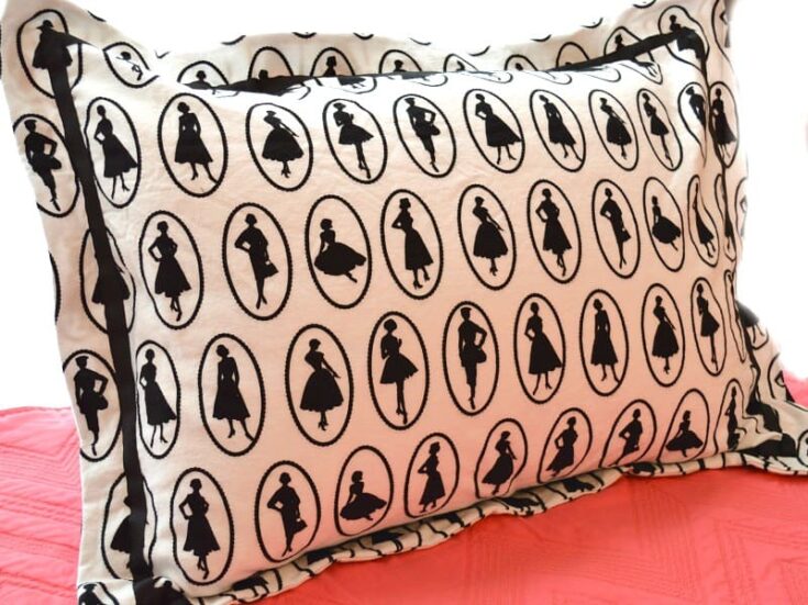 black and white patterned pillow on pink quilt.
