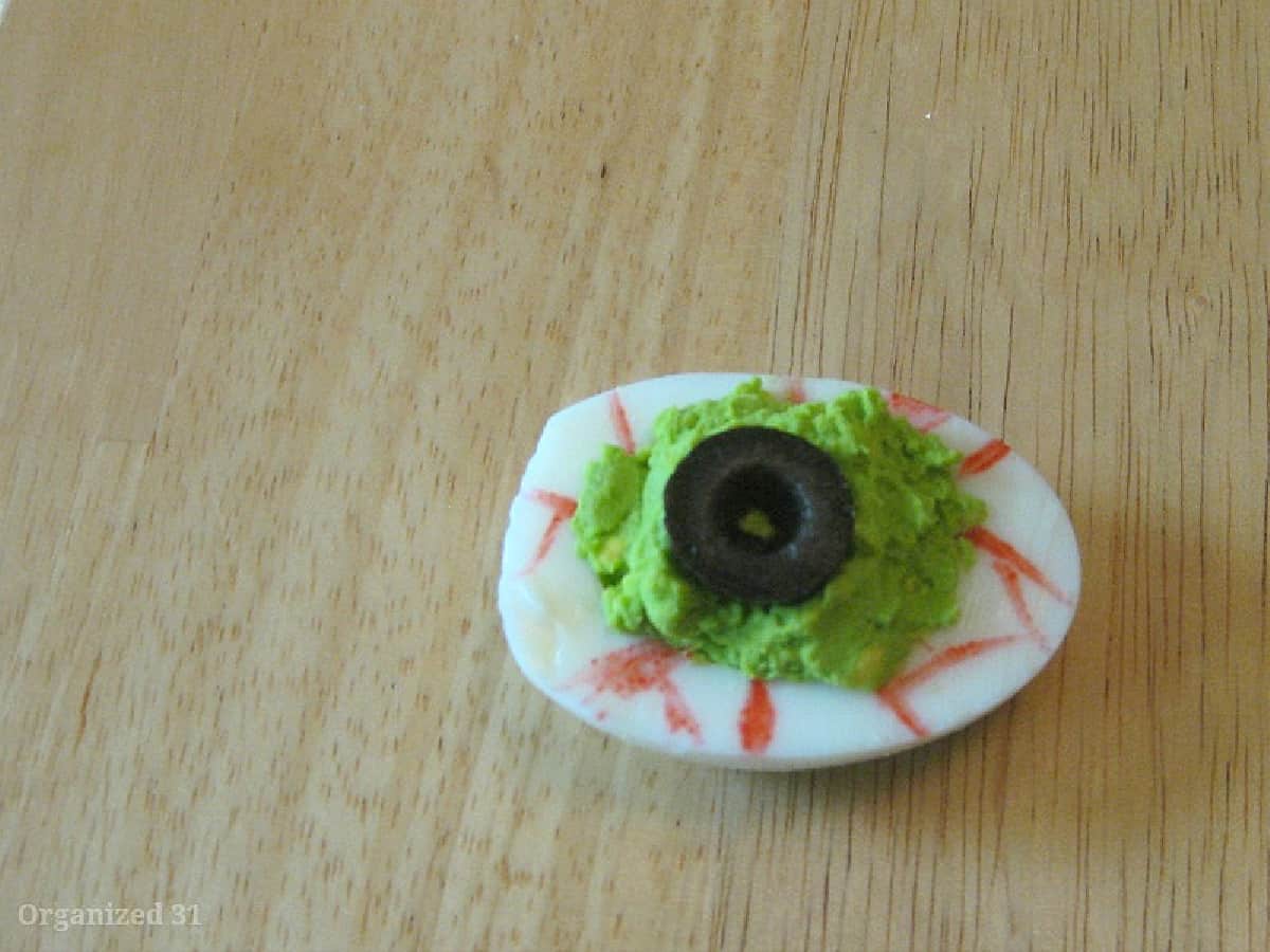 overhead view of one deviled egg decorated to look like scary eyeball.