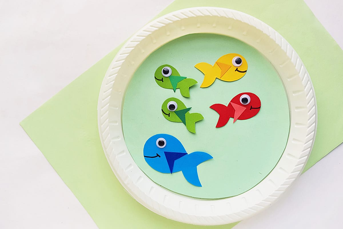 paper plate craft with colorful fish on green background.