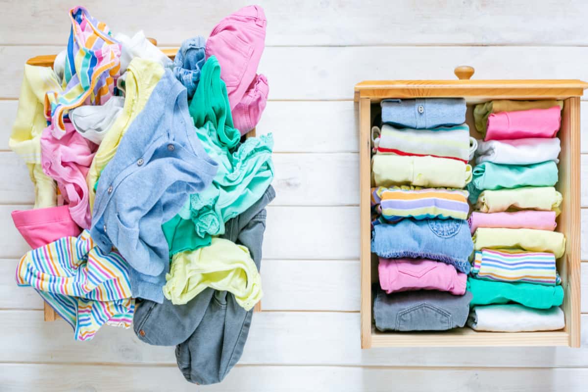overhead view of pile of colorful unfolded clothes next to neatly folded clothes in drawer.