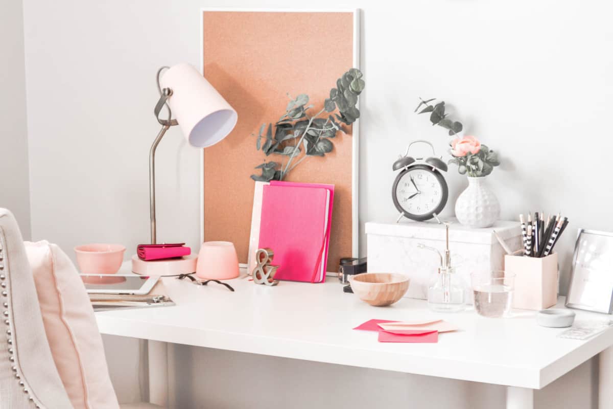 A white neat and tidy desk with a pink chair.