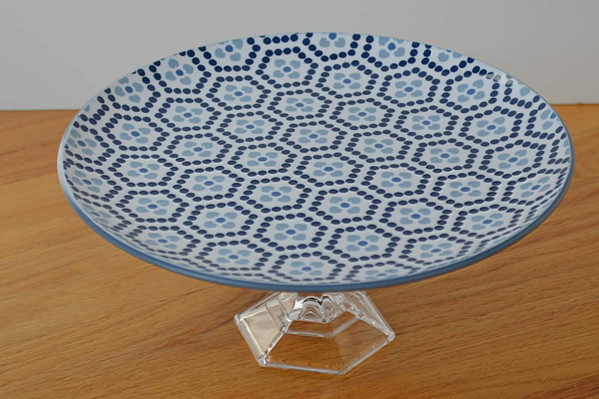 A blue and white plate on a wooden stand.