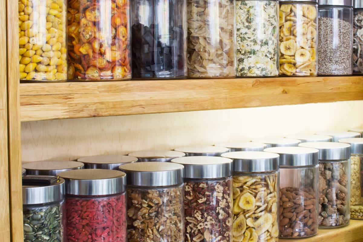 A wooden shelf with jars of nuts and seeds.